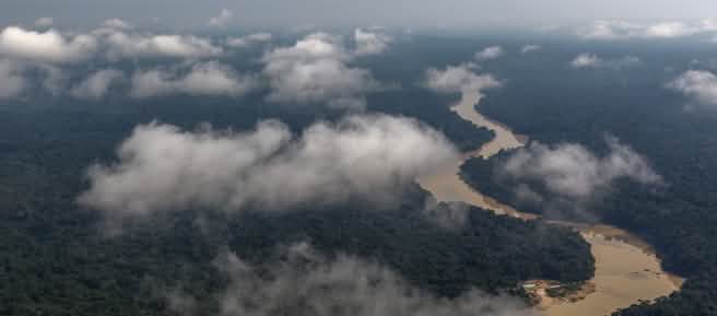 Fotografia aérea com nuvens e rio sinuoso passando pela floresta tropical