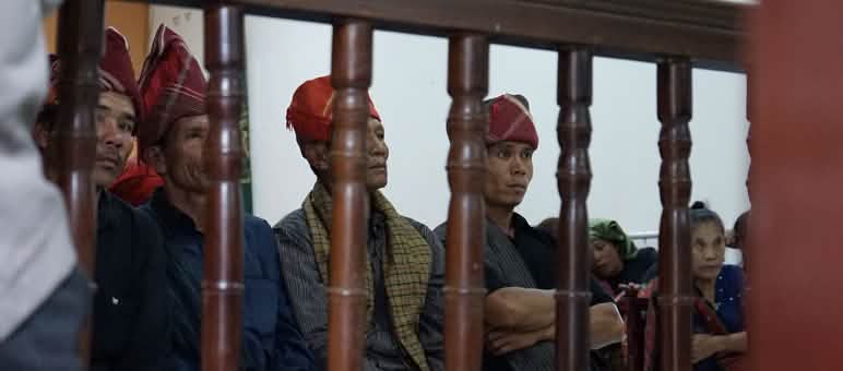 Em vez de reconhecer os indígenas e os seus territórios, eles são perseguidos e encarcerados Homens com cabeças cobertas da forma típica dos Batak sentados atrás das grades