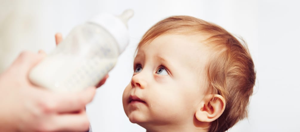 Um bebê recusa uma mamadeira