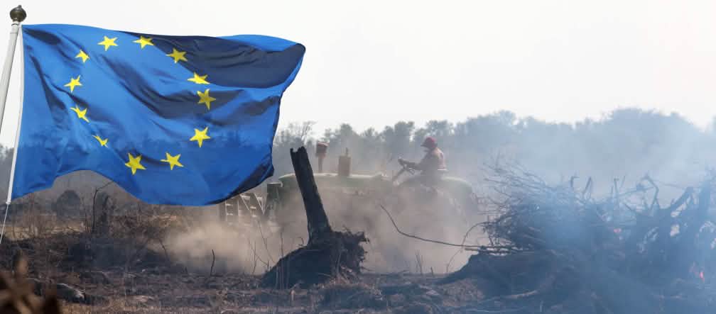 Fotomontagem: A bandeira da UE explode na frente de um trator que remove a vegetação