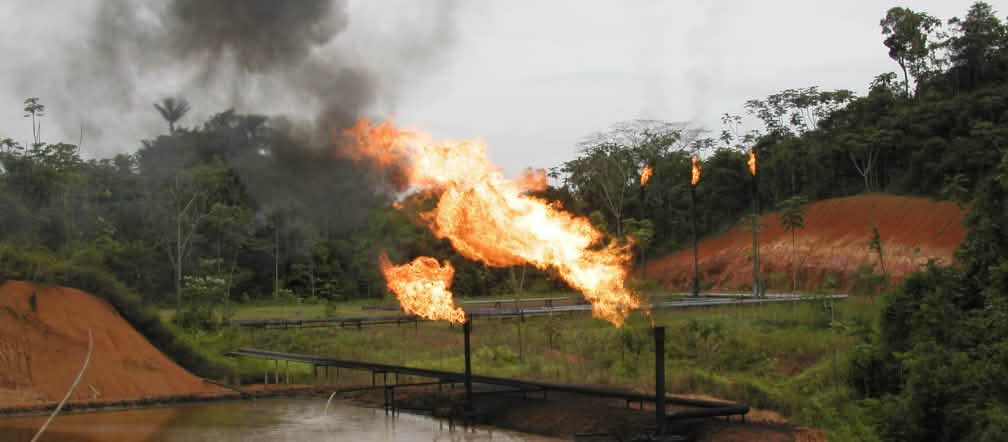 Tochas de fogo da indústria petrolífera na Amazônia equatoriana Gas flaring, tubulações e “lago” de petróleo na floresta tropical