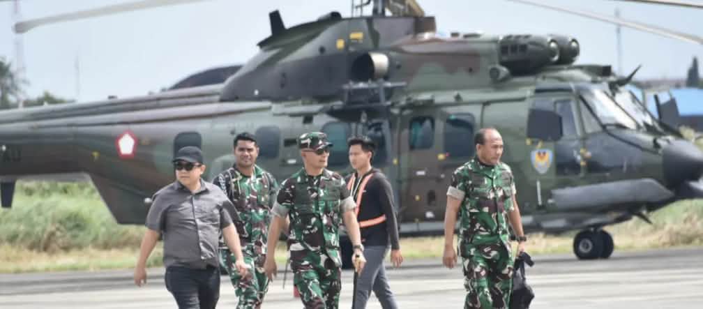 Militar protegendo o projeto de açúcar e bioetanol em Merauke Três soldados e dois civis andando em frente de um helicóptero