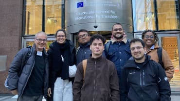 Foto de grupo de 7 pessoas à frente da entrada de um prédio da Comissão Européia em Bruxelas l