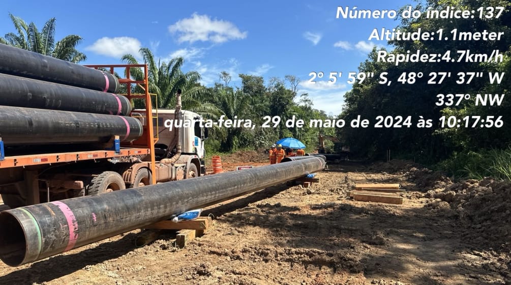 Um caminhão com seções de tubulação de dutos e seções de tubulação já colocadas no chão em um local de construção na floresta tropical